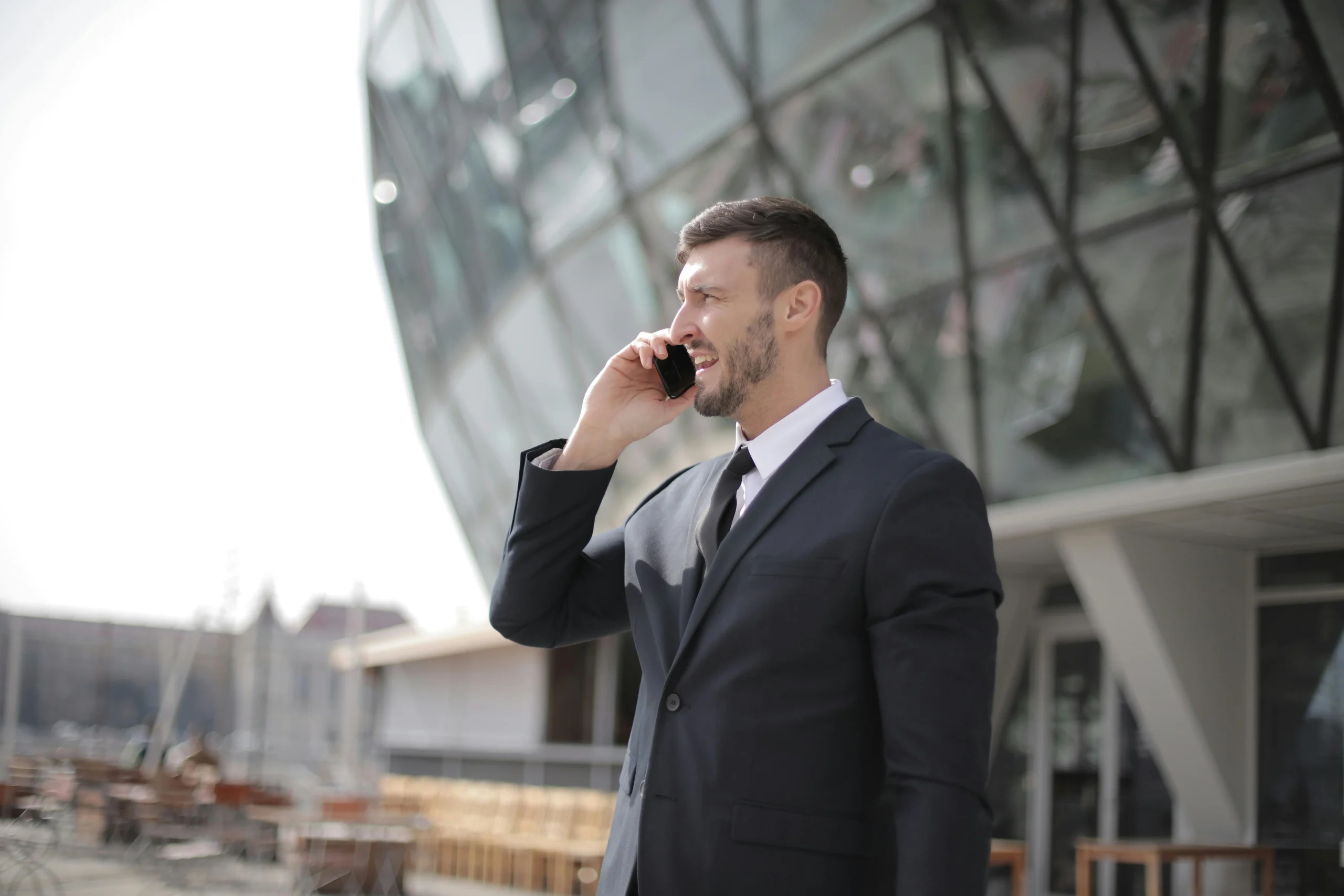 Businessman in a suit talking on the phone outside a modern glass building