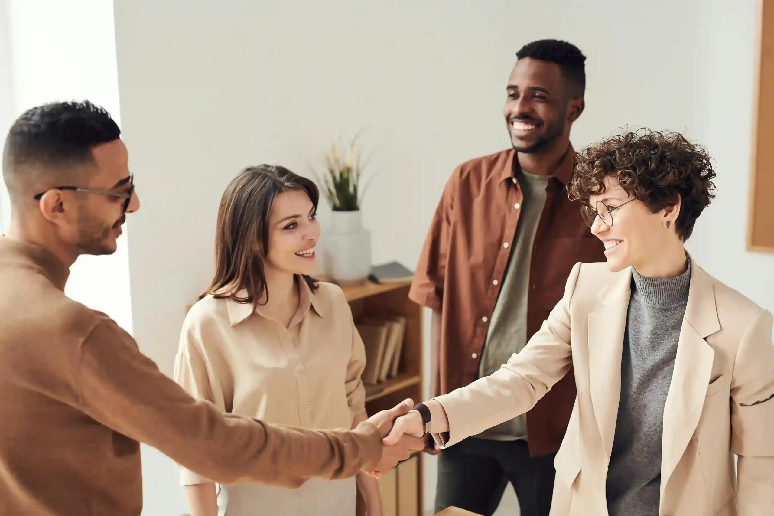 Diverse group of professionals smiling and shaking hands in a modern office setting