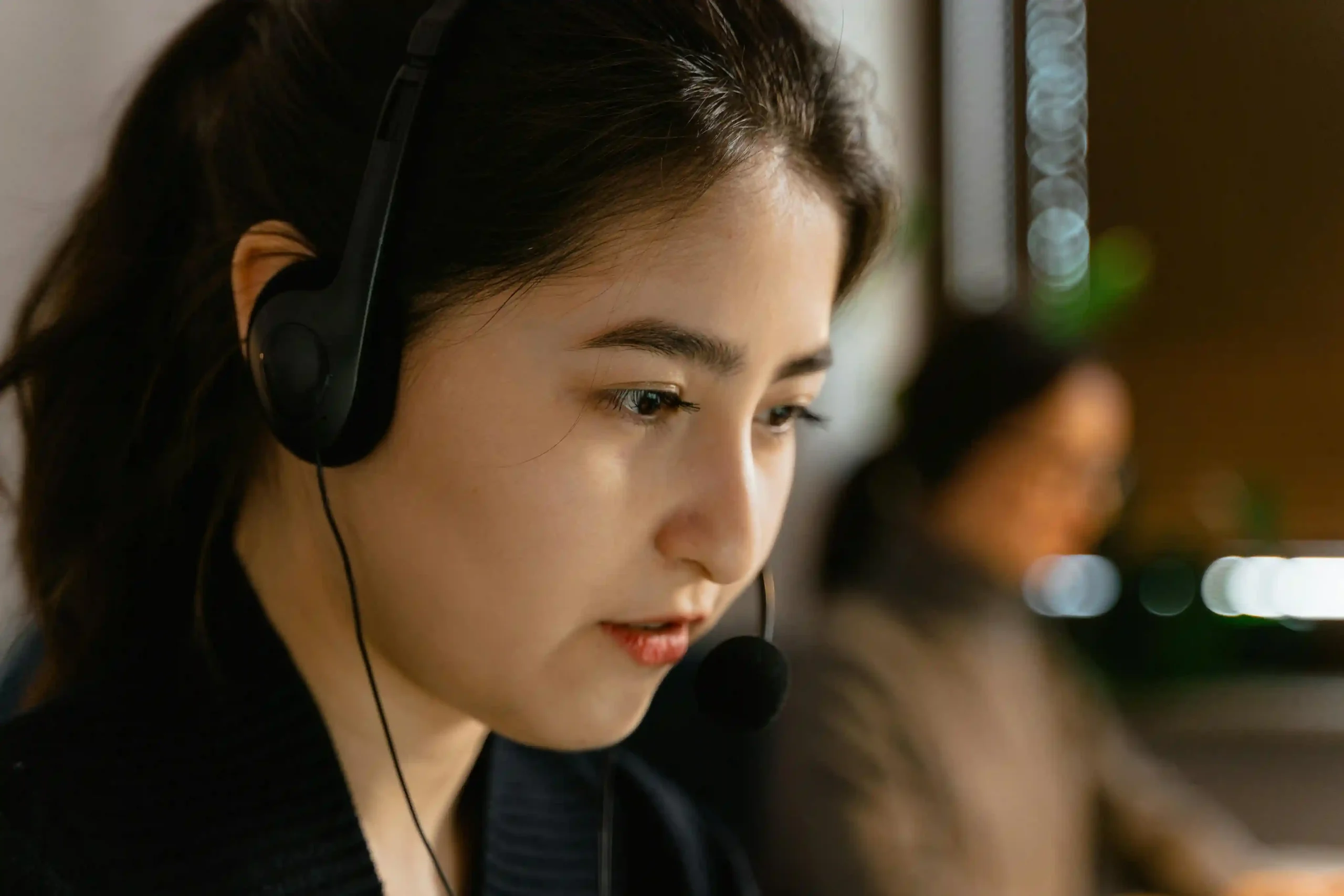 A focused customer support representative wearing a headset, working in a call center